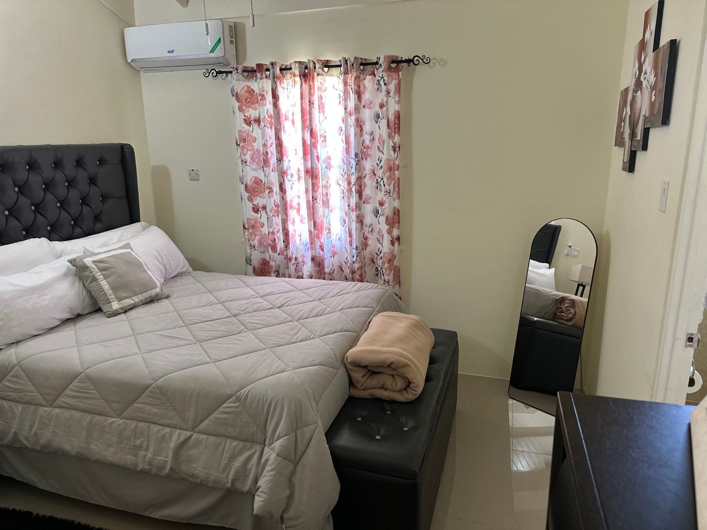 Queen bedroom with a tufted headboard and floral curtains
