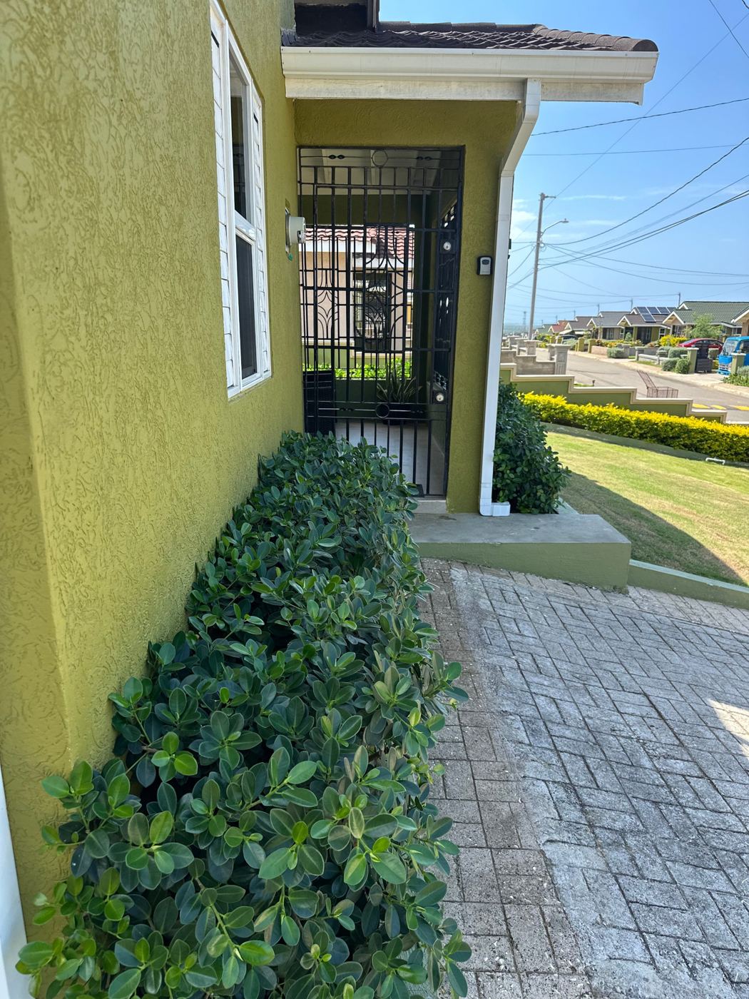 Front entrance with a secure gate and landscaped hedges
